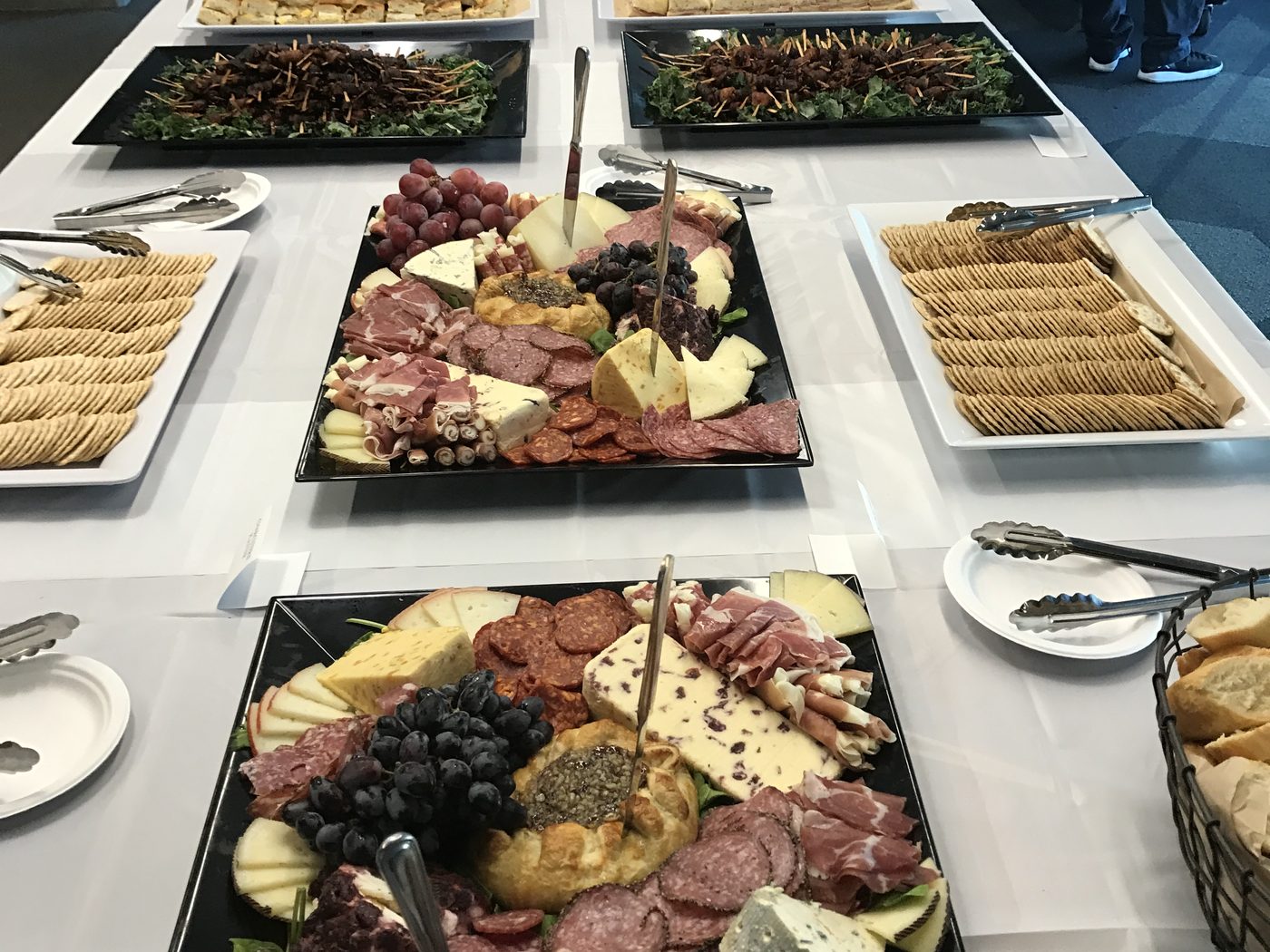 Office catering buffet on white linen with charcuterie and cracker platters at a Bay Area company